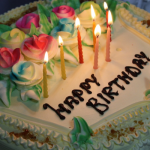 Fødselsdagskage med tændte lys og Happy Birthday-tekst