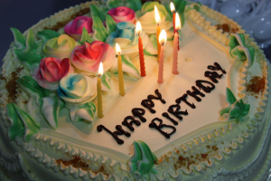 Fødselsdagskage med tændte lys og Happy Birthday-tekst