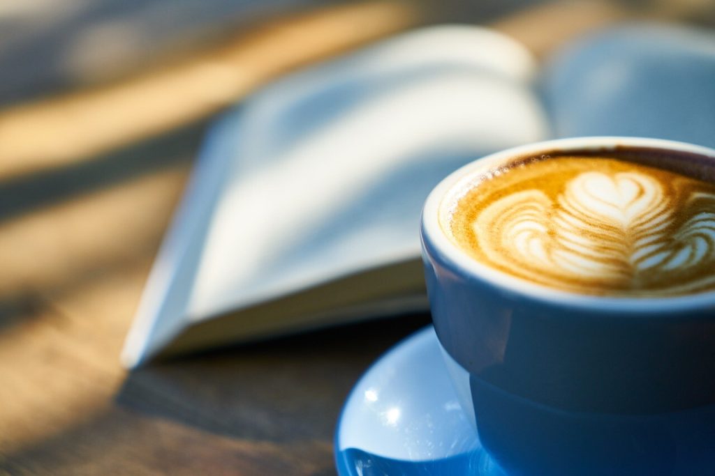 Kaffe med mælkeskumshjerte ved opslået bog