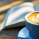 Kaffe med mælkeskumshjerte ved opslået bog