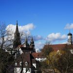 Kirketårne og spir over bytage mod blå himmel