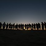 Silhuetter af mennesker hånd i hånd ved solnedgang