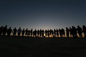 Silhuetter af mennesker hånd i hånd ved solnedgang