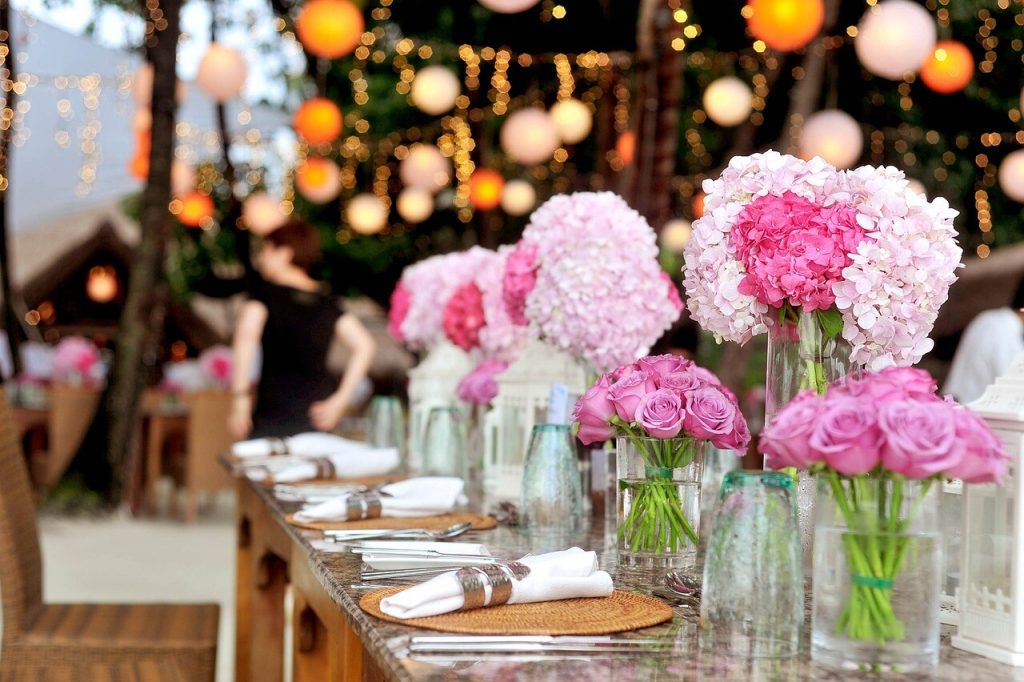 Festbord pyntet med lyserøde blomsterbuketter og lyskæder