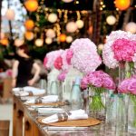 Festbord pyntet med lyserøde blomsterbuketter og lyskæder