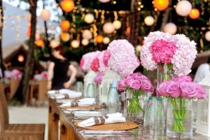 Festbord pyntet med lyserøde blomsterbuketter og lyskæder