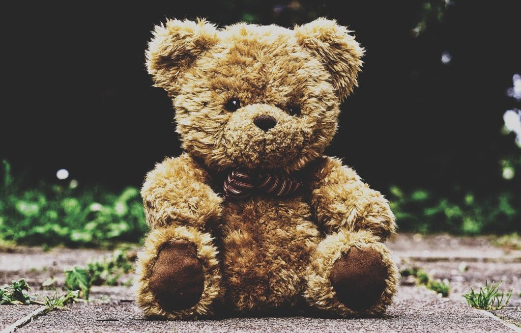 Bamse med sløjfe sidder på fliser