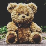 Bamse med sløjfe sidder på fliser