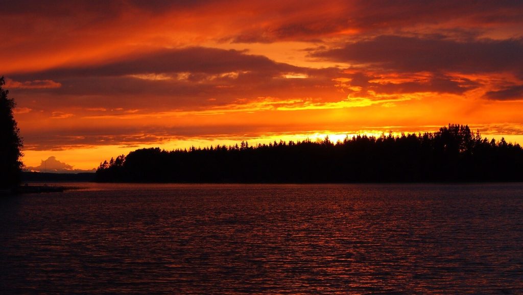 Orange solnedgang over sø og skov