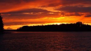 Orange solnedgang over sø og skov