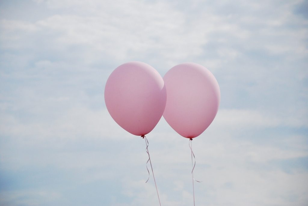 To lyserøde balloner mod himlen