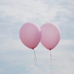 To lyserøde balloner mod himlen