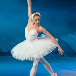 Ballerina i hvid tutu danser på scene