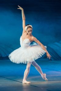 Ballerina i hvid tutu danser på scene