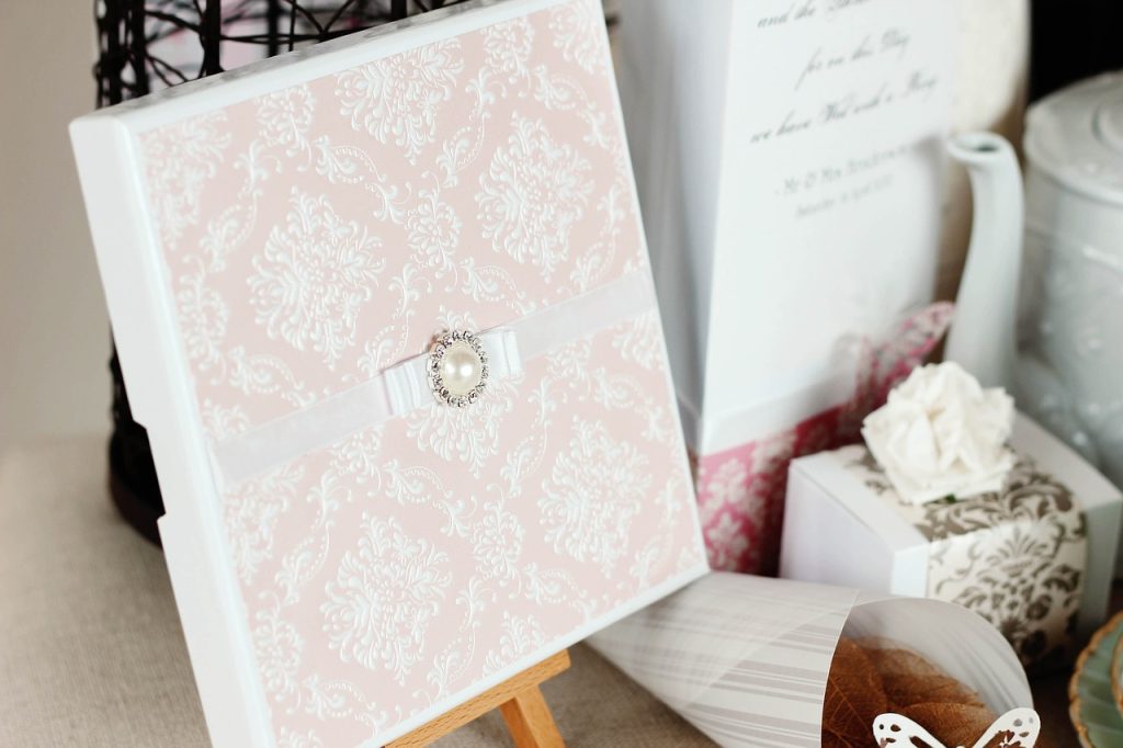 Elegant invitationskort med sløjfe og perle